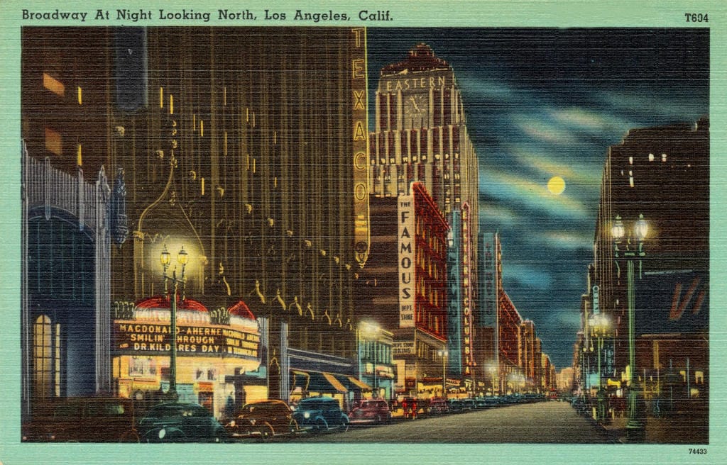 A brightly coloured vintage postcard of a city street at night under a full moon.