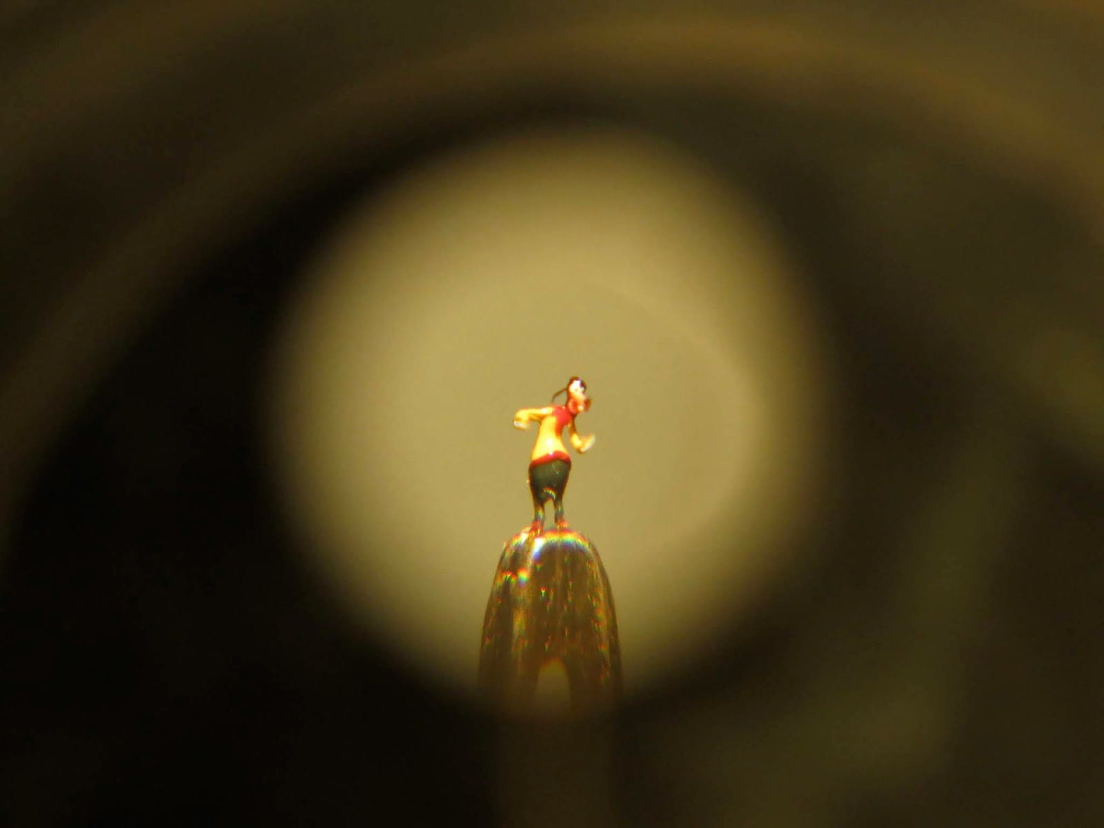 Darkly vingetted image of the eye of a needle with an anthropomorphised dog