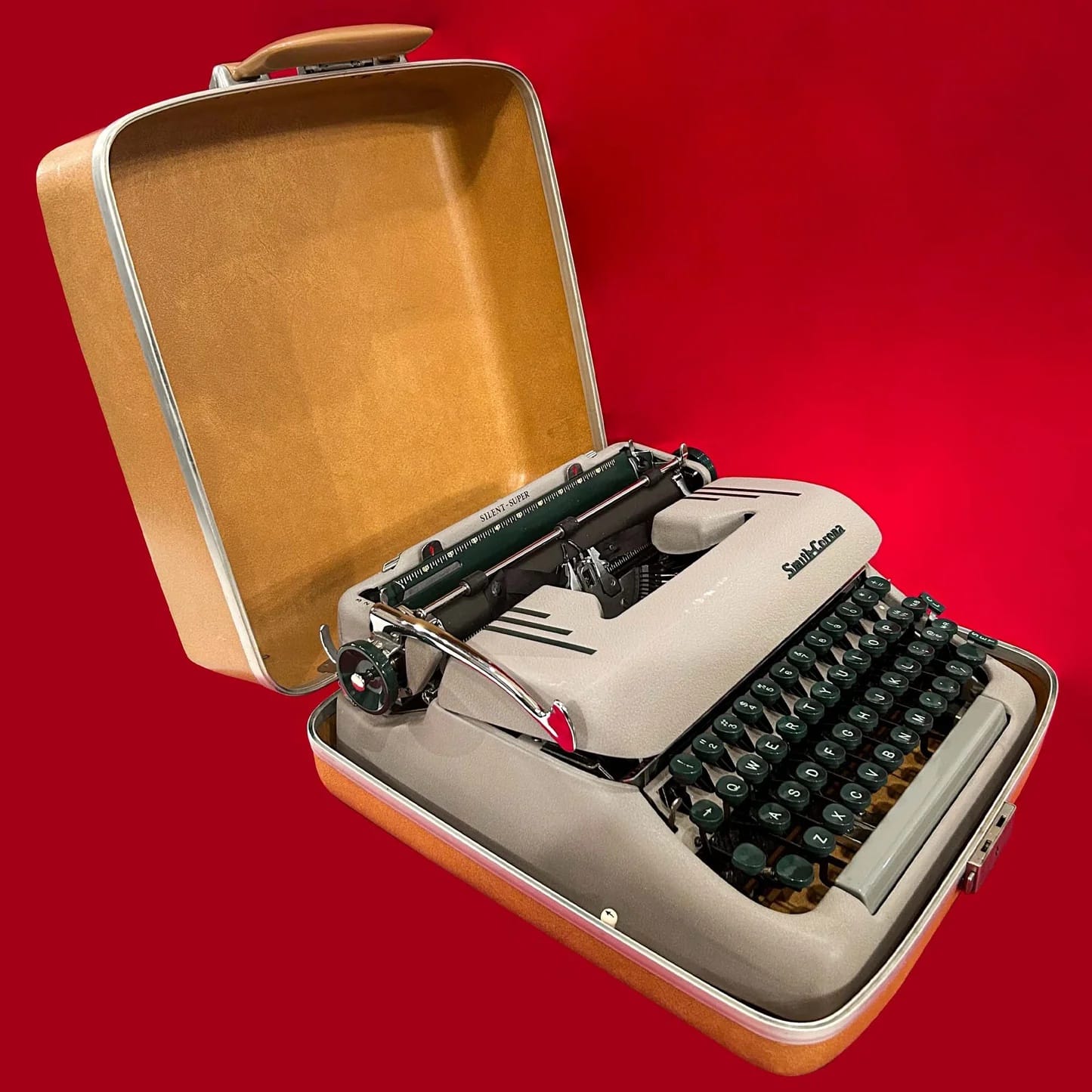 An old beige typewriter in a hard case with a handle